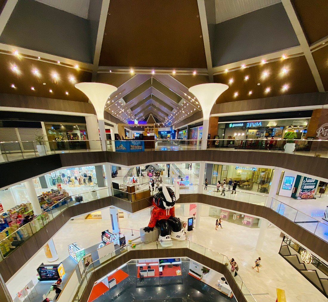 Outdoor food market with tents and people gathered, tall buildings in background.
