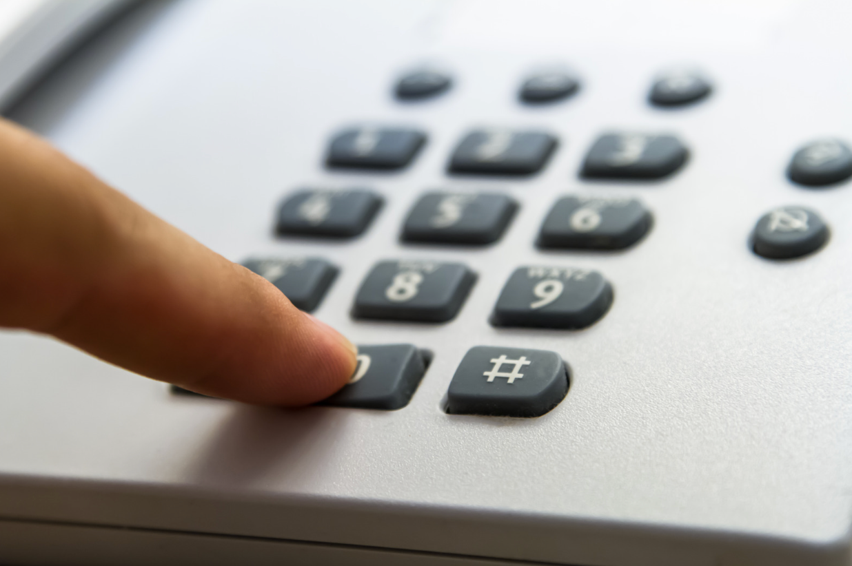 A person is pressing the number 2 button on a telephone