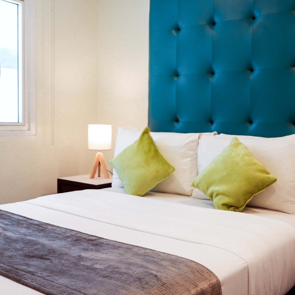 An affordable hotel room with a large bed and a green chair at The Exchange Regency Hotel