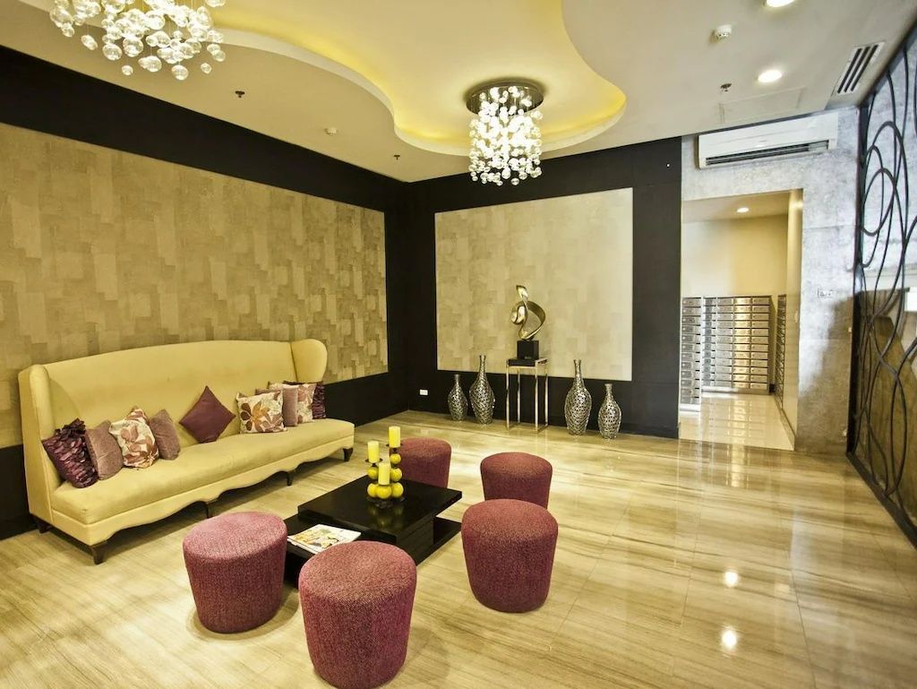 A living room with a couch , table , ottomans and a chandelier at The Exchange Regency