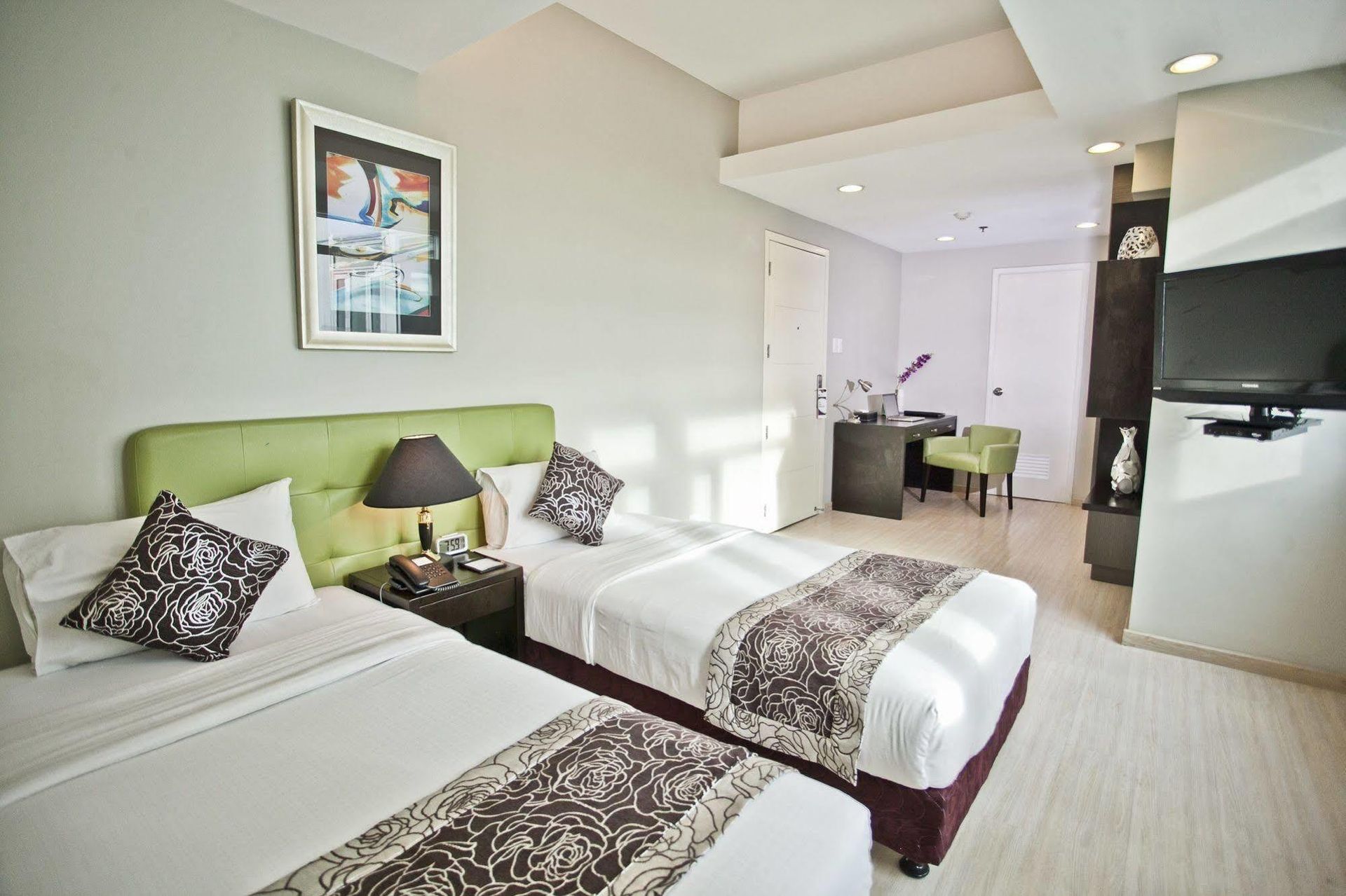 A hotel room with two beds , a desk and a television.