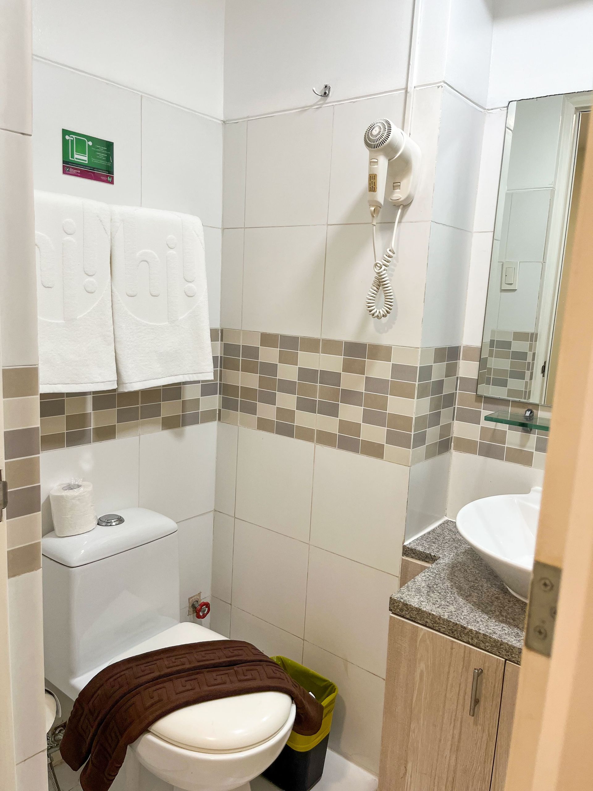 A bathroom with a toilet , sink and mirror.
