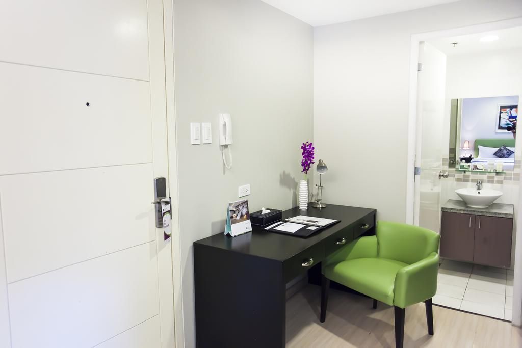 A hotel room with a desk and a green chair
