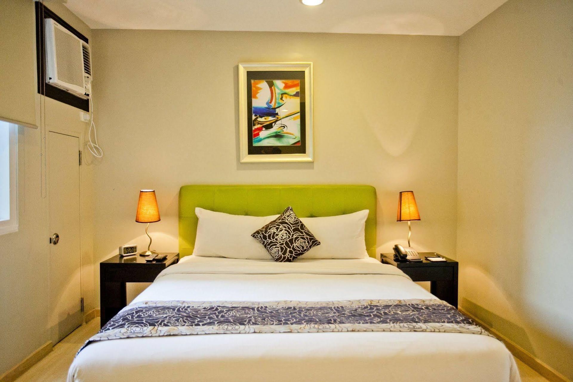 A hotel room with a bed and two lamps