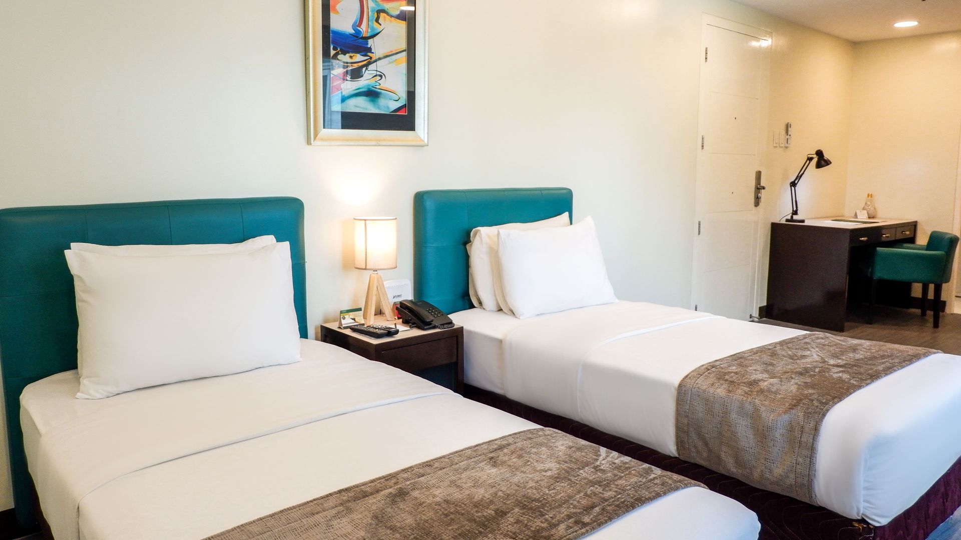 A hotel room with two beds and a desk.