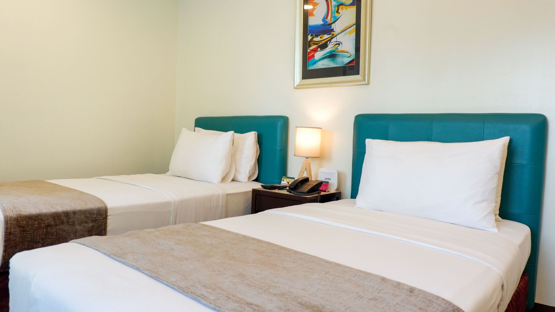 A hotel room with two beds and a picture on the wall.