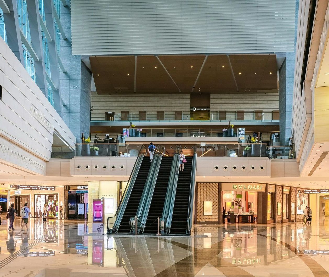 Mall interior with escalators, shops, and people; a bright, modern setting.