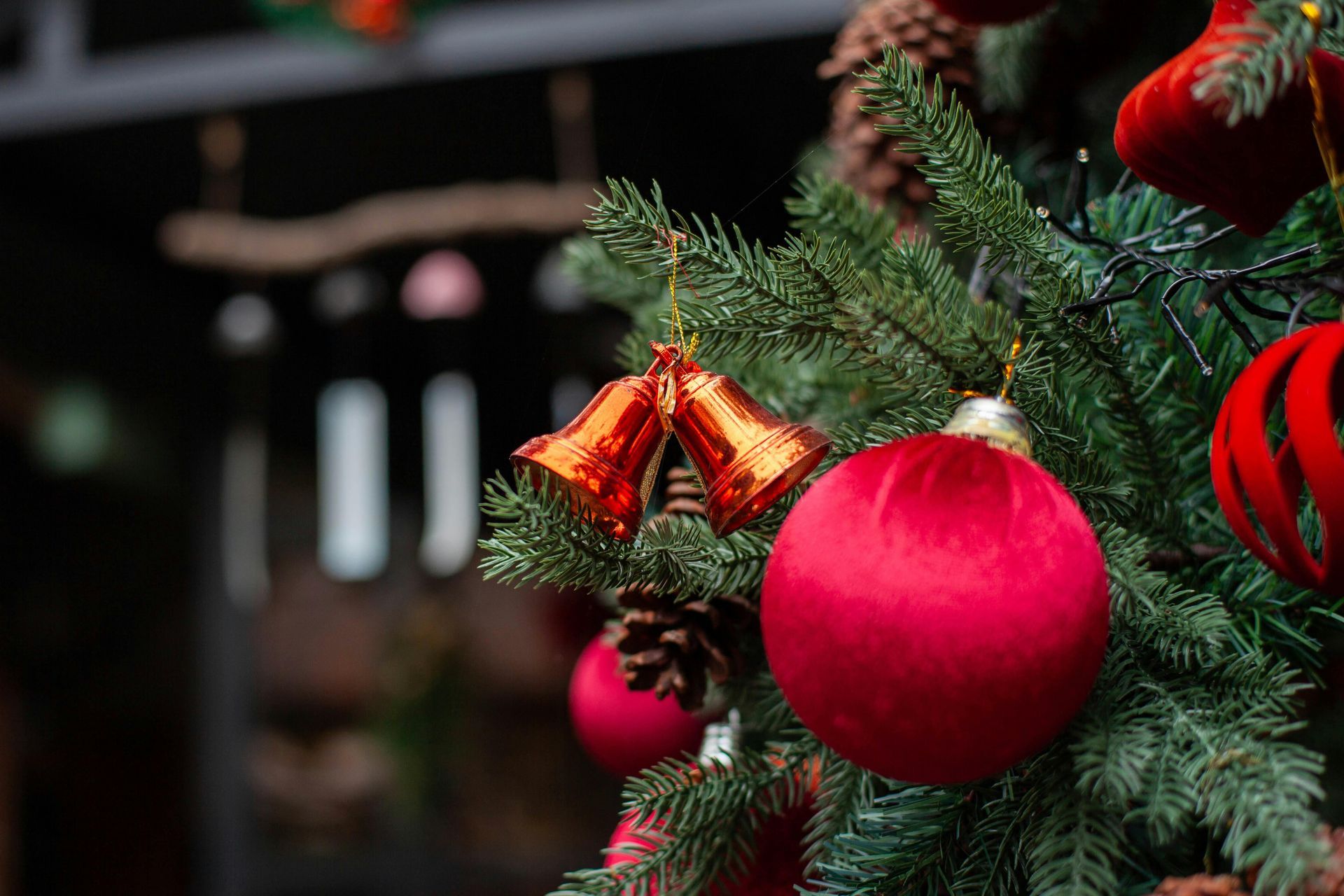 Close-up of a decorated Christmas tree with red ornaments, bells, and pinecones.