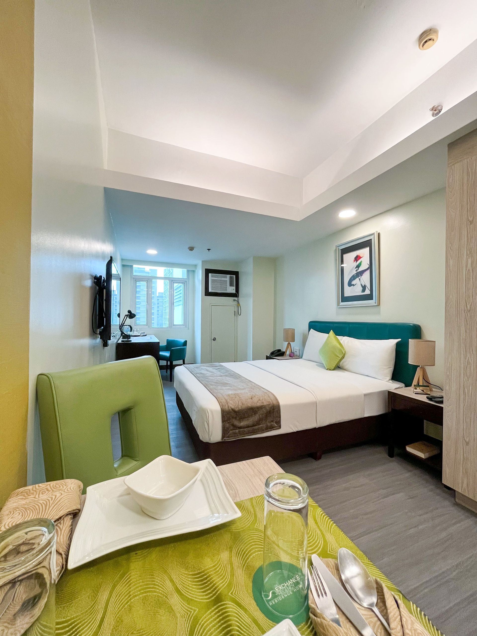 A hotel room with a king size bed and a table with plates and utensils on it.