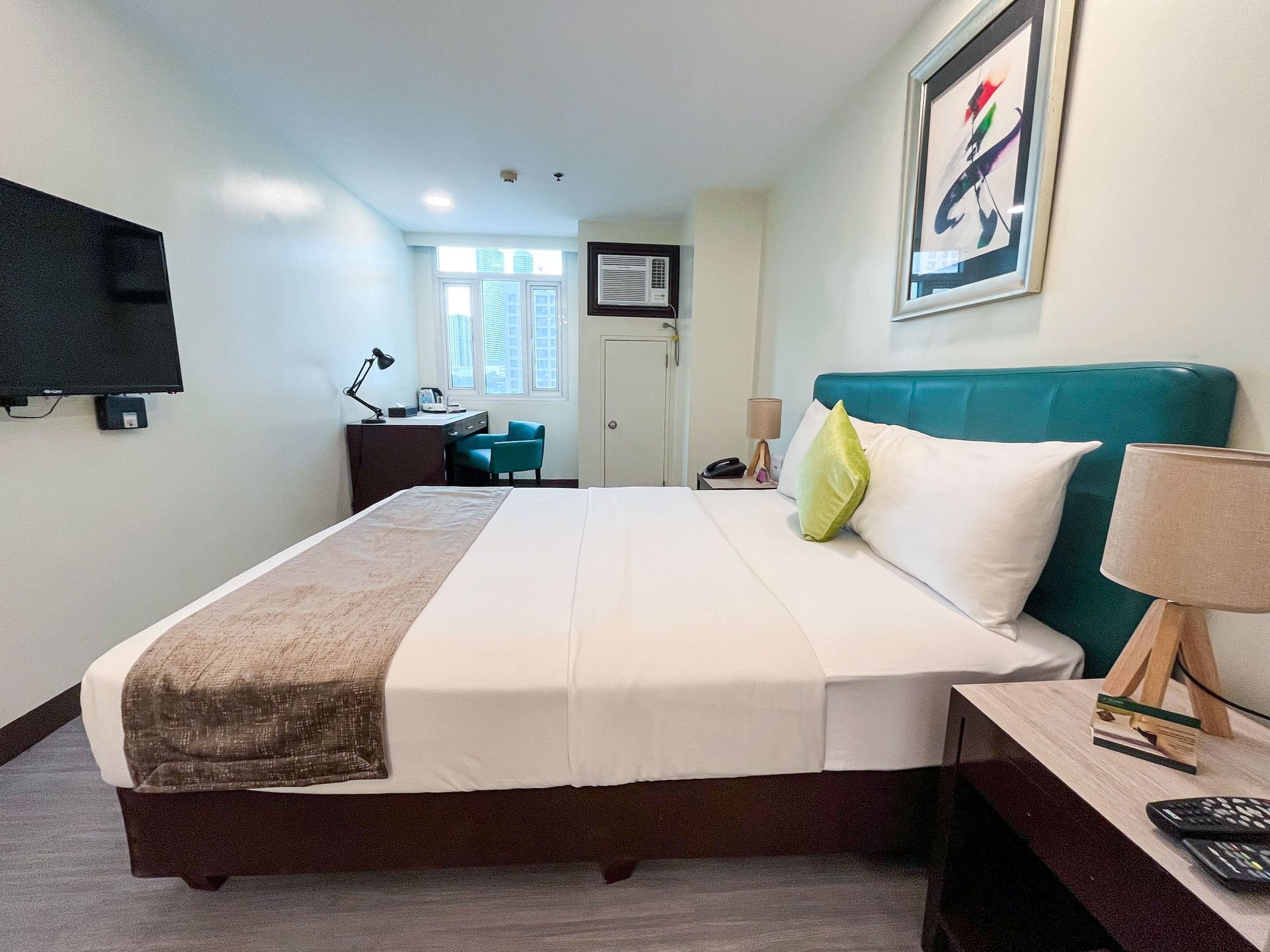 A hotel room with a king size bed and a flat screen tv.