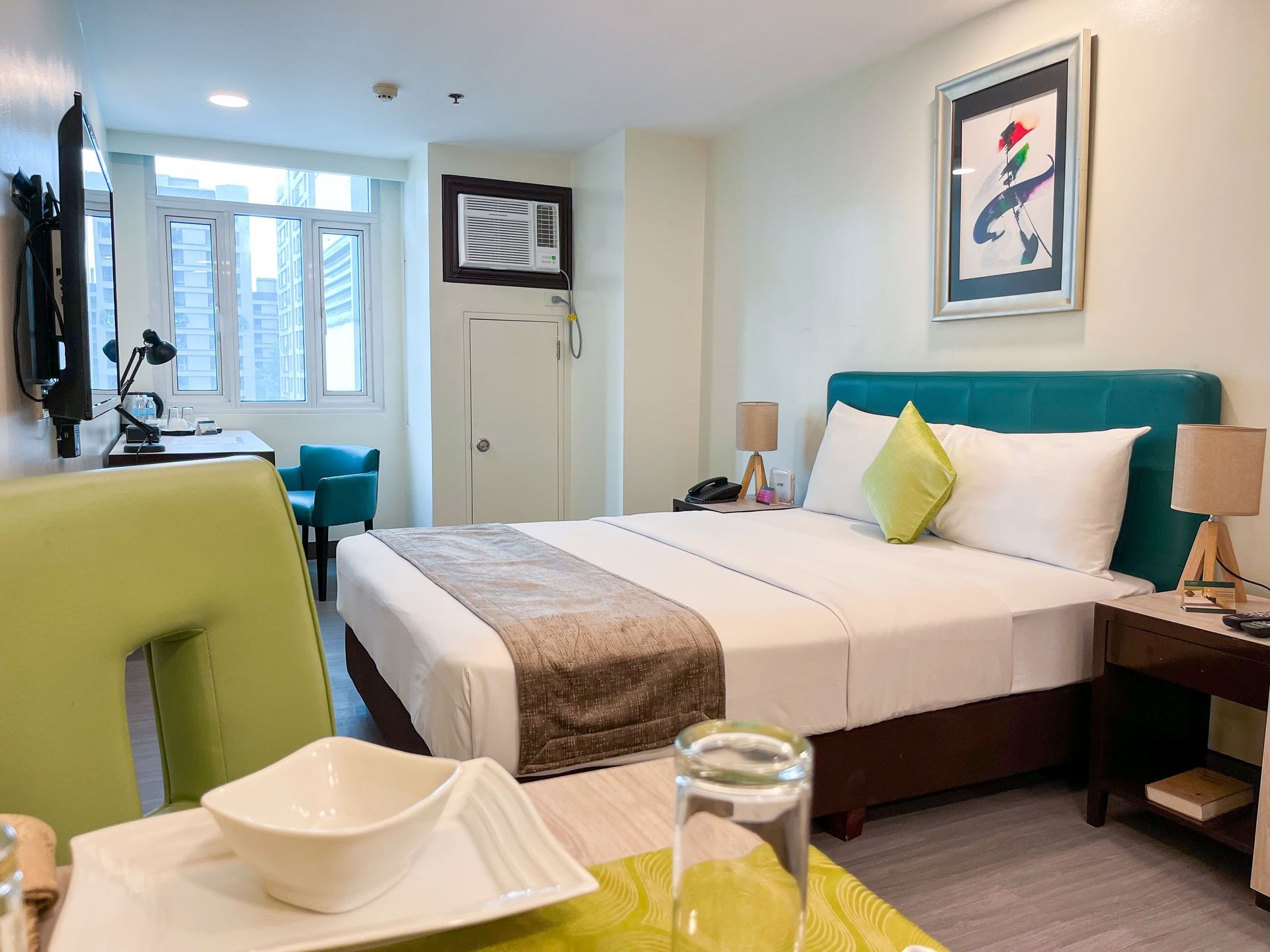 A hotel room with a large bed and a table with plates for your affordable staycation in Pasig