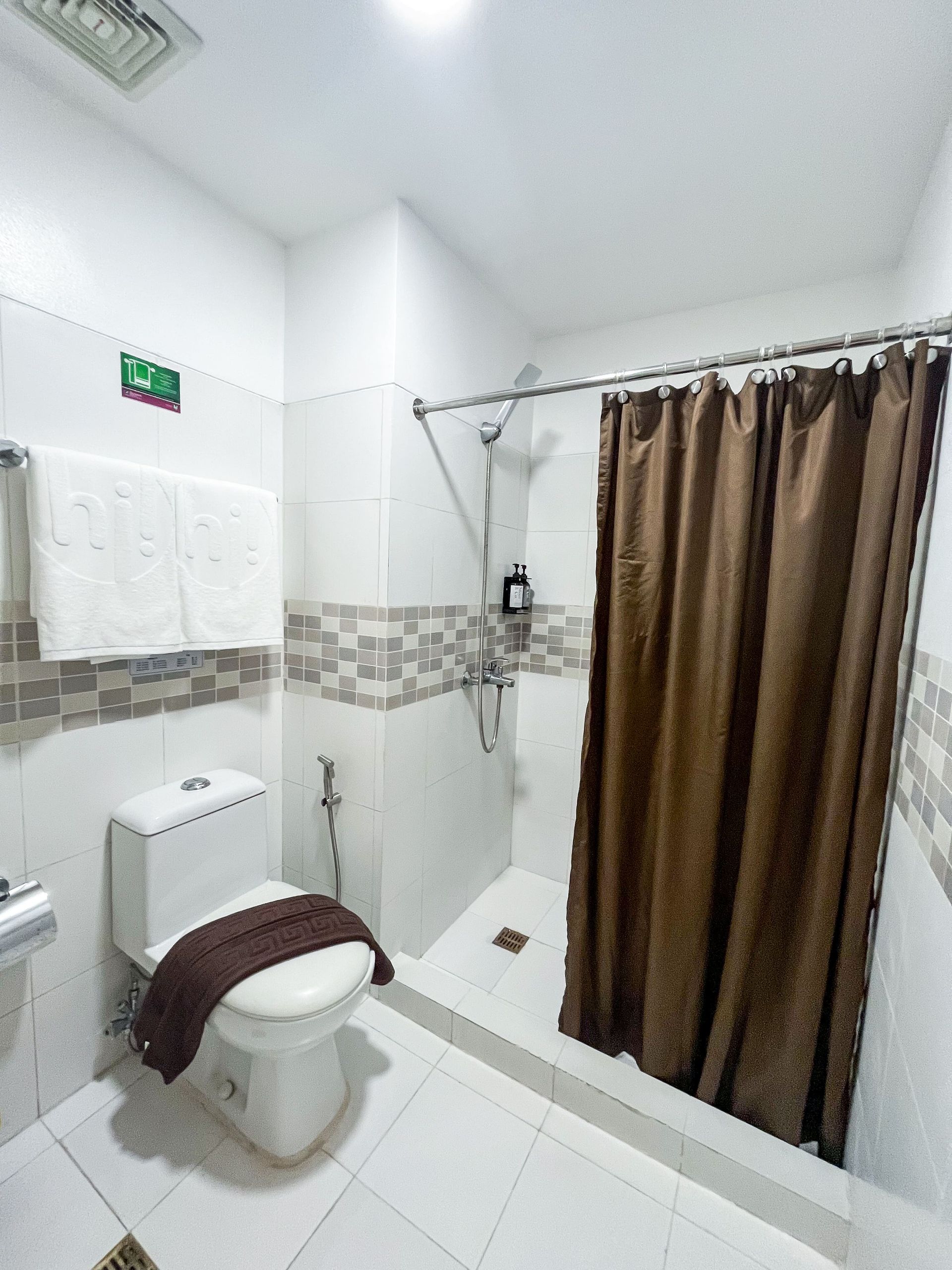 A bathroom with a toilet and shower with a brown curtain