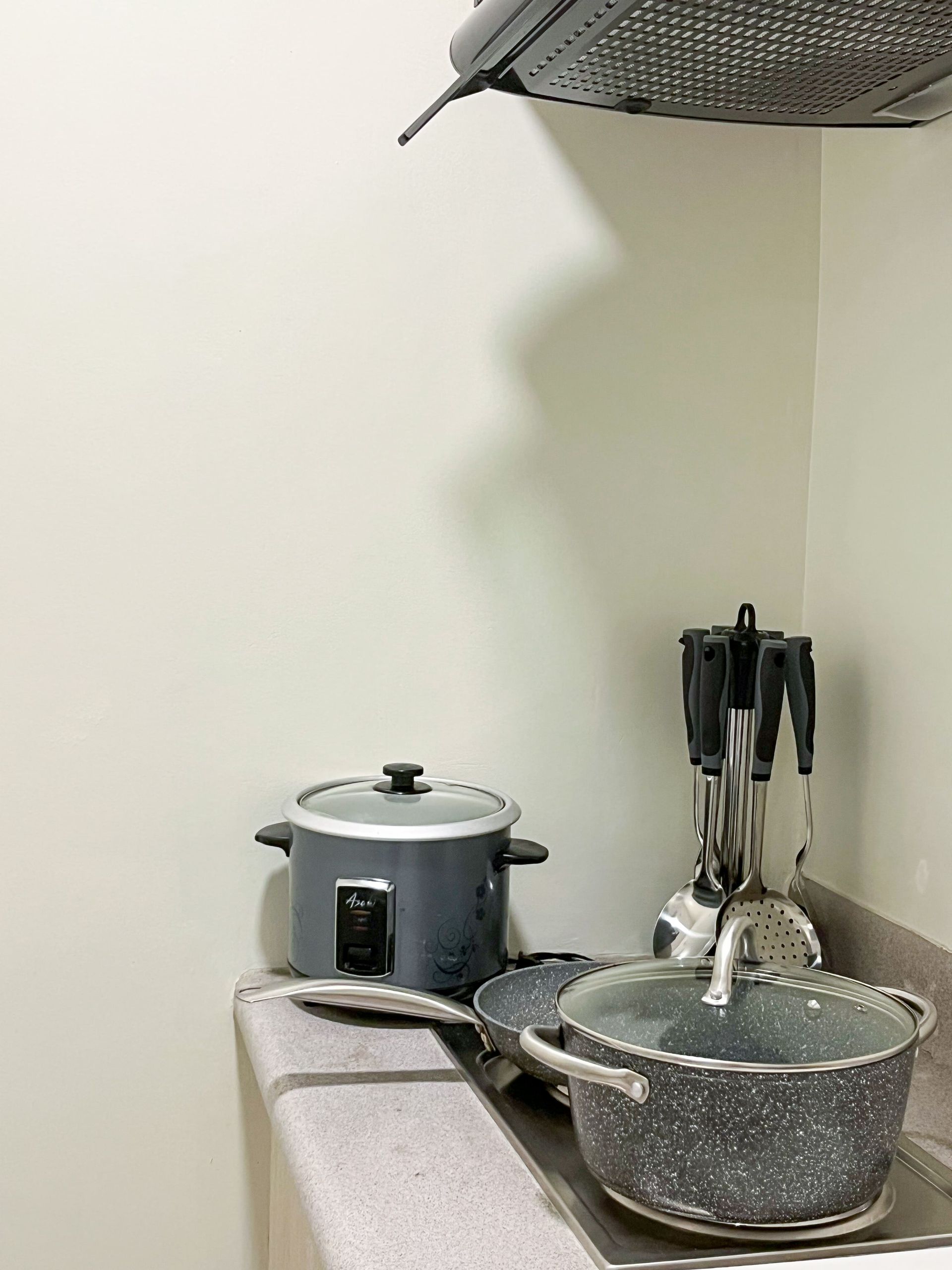 A kitchen counter with pots and pans and a blender on it.