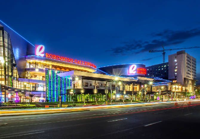 Night view of Robinsons Galleria with bright red and white signs and lights along the road.