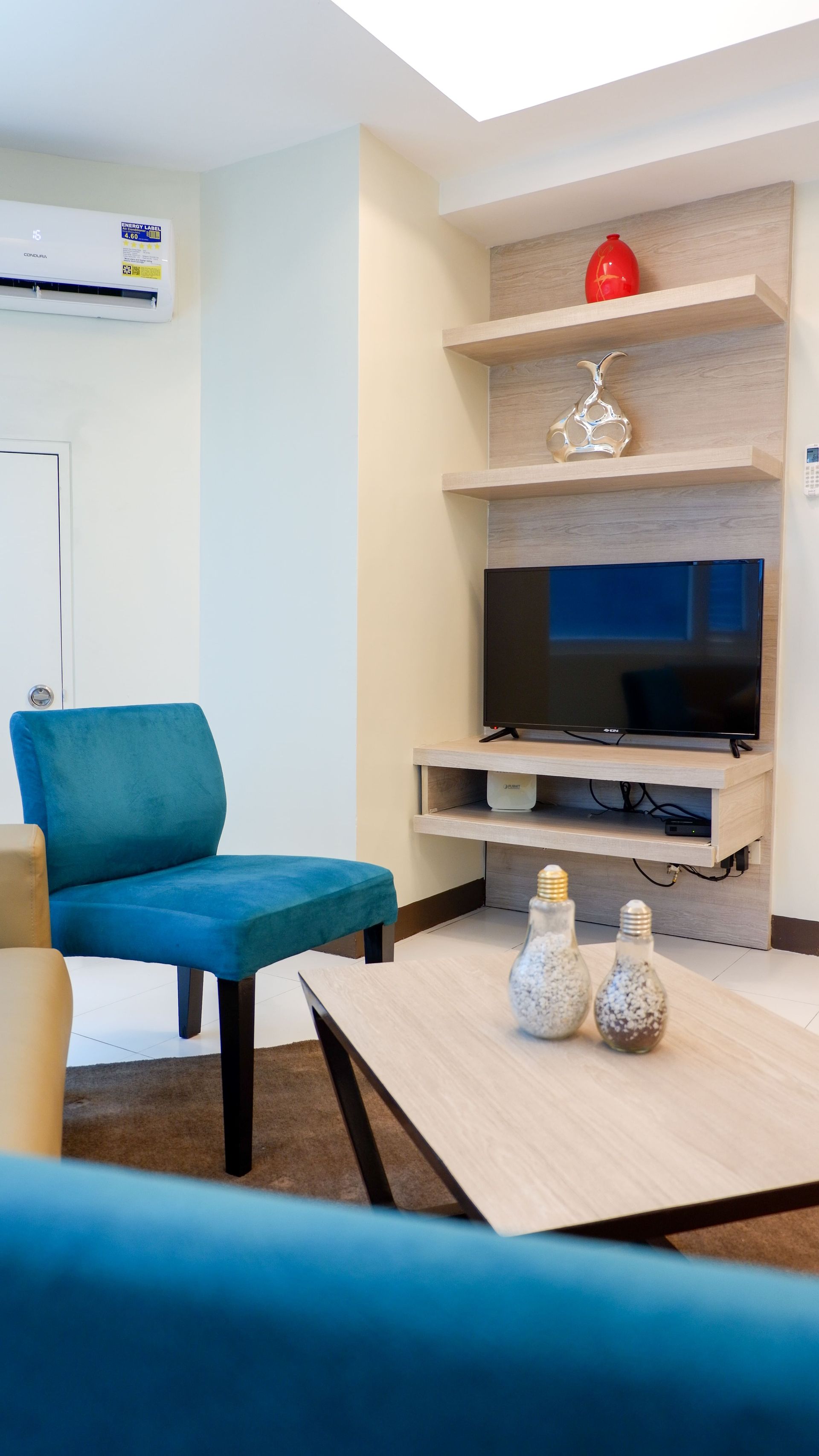 A living room with a couch, chair, table, and television in a hotel in Pasig
