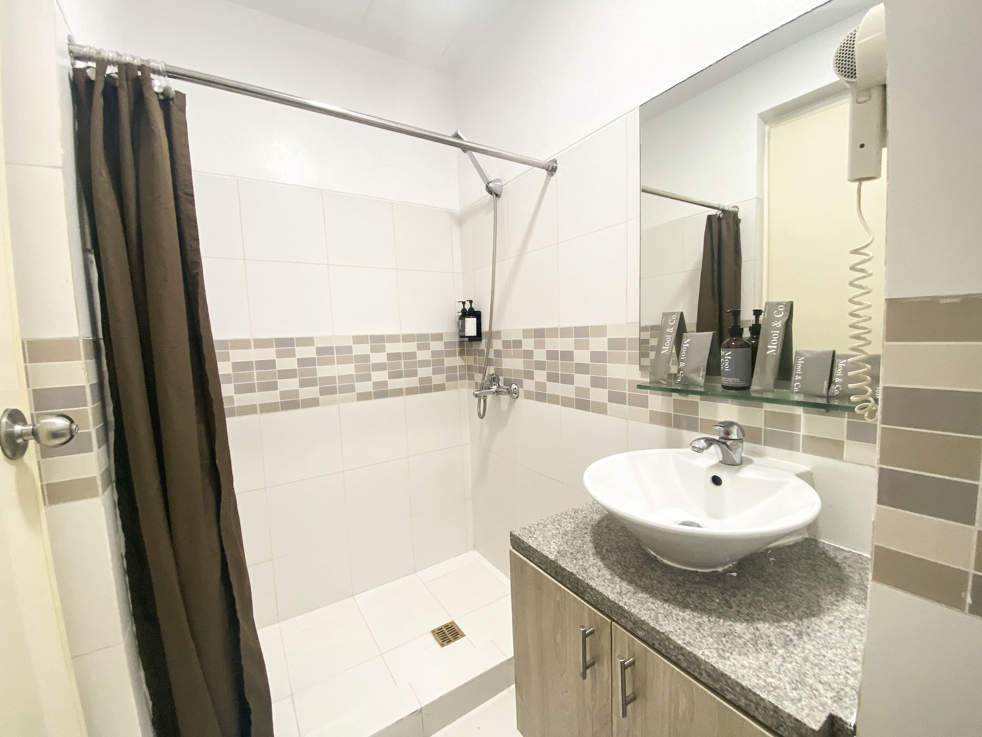 A bathroom with a sink , shower and mirror.