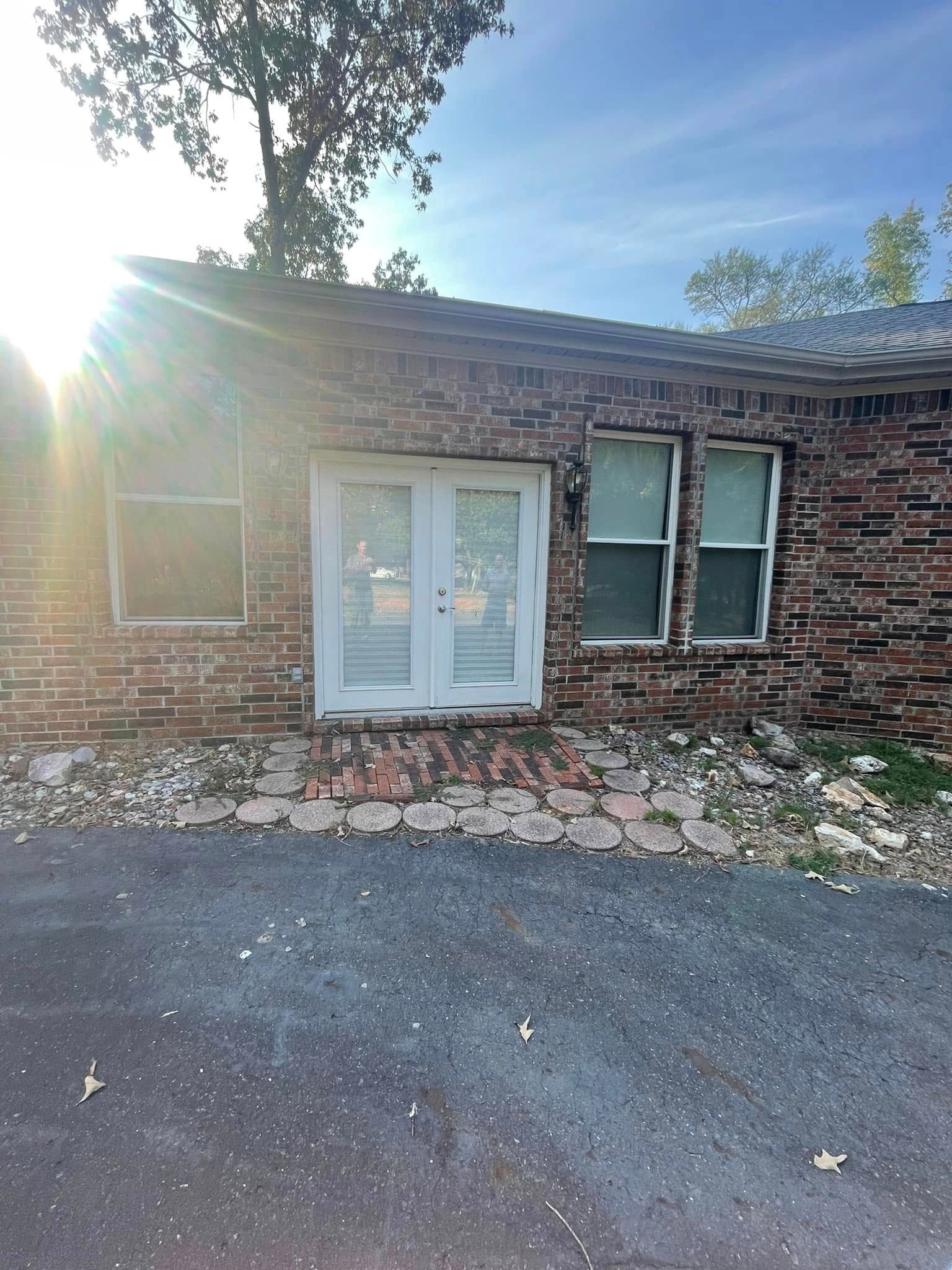 Brick building with double doors, two windows, and sun flare.