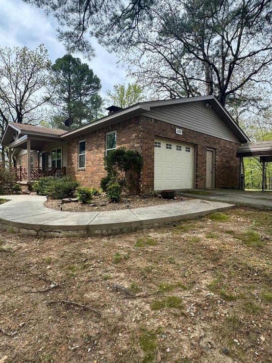 A brick house with a white garage door is for sale.