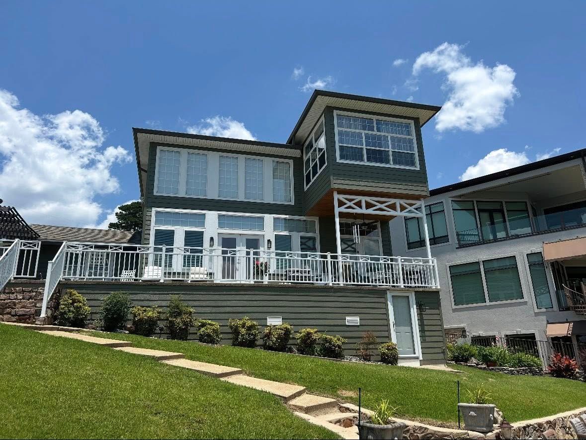 A blue house with a white roof is behind a chain link fence.