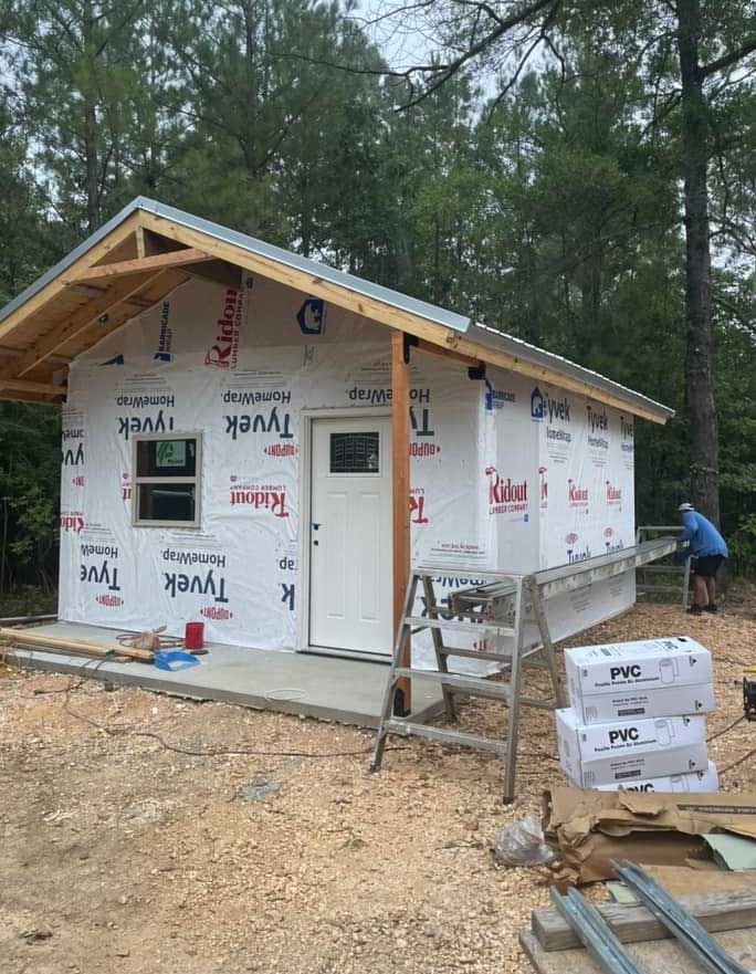 A small house is being built in the middle of a forest.