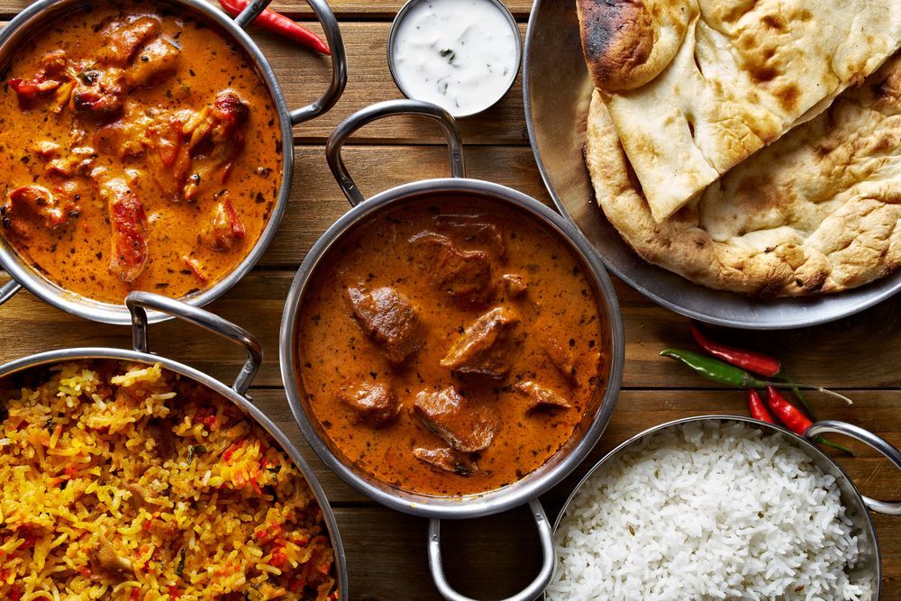 Indian Food Spread: Curries, Rice, Naan, And Yogurt Dip.
