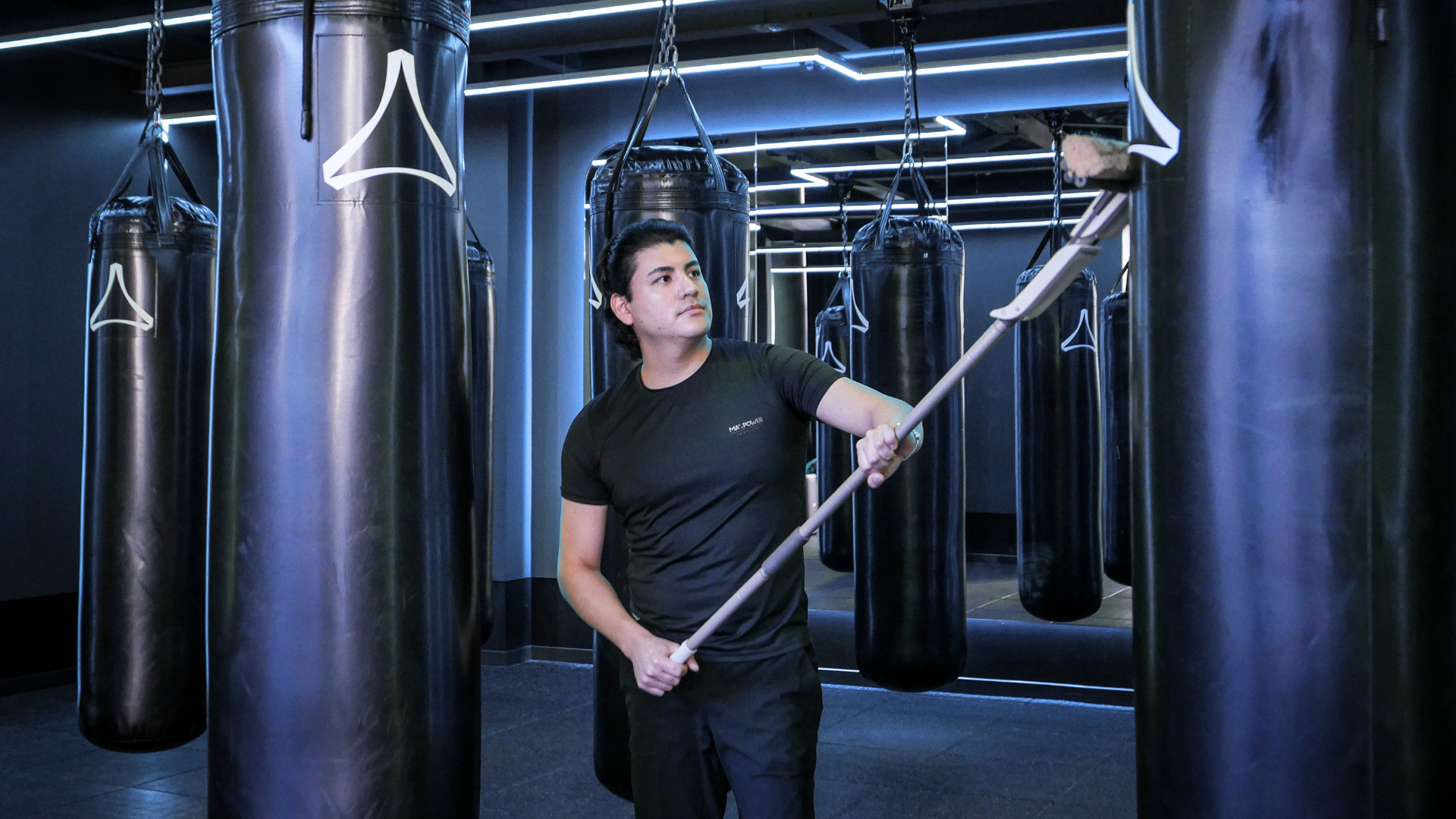 Person with cleaning cart in a hallway, holding gloves. Wet floor sign visible.