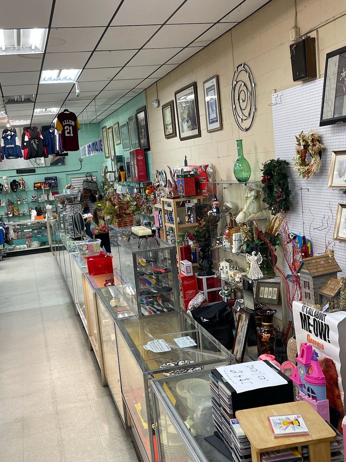 Inside a shop, glass display cases with merchandise line the walls. Assorted items and decorations are visible.