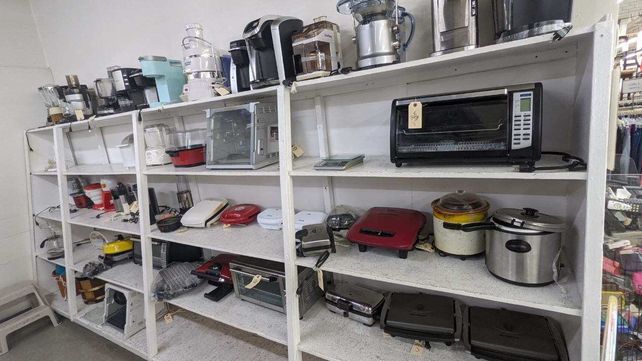 Shelves filled with various kitchen appliances for sale.