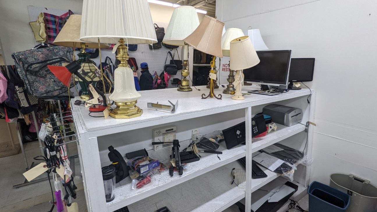 White shelf displaying lamps, computer monitors, and accessories.