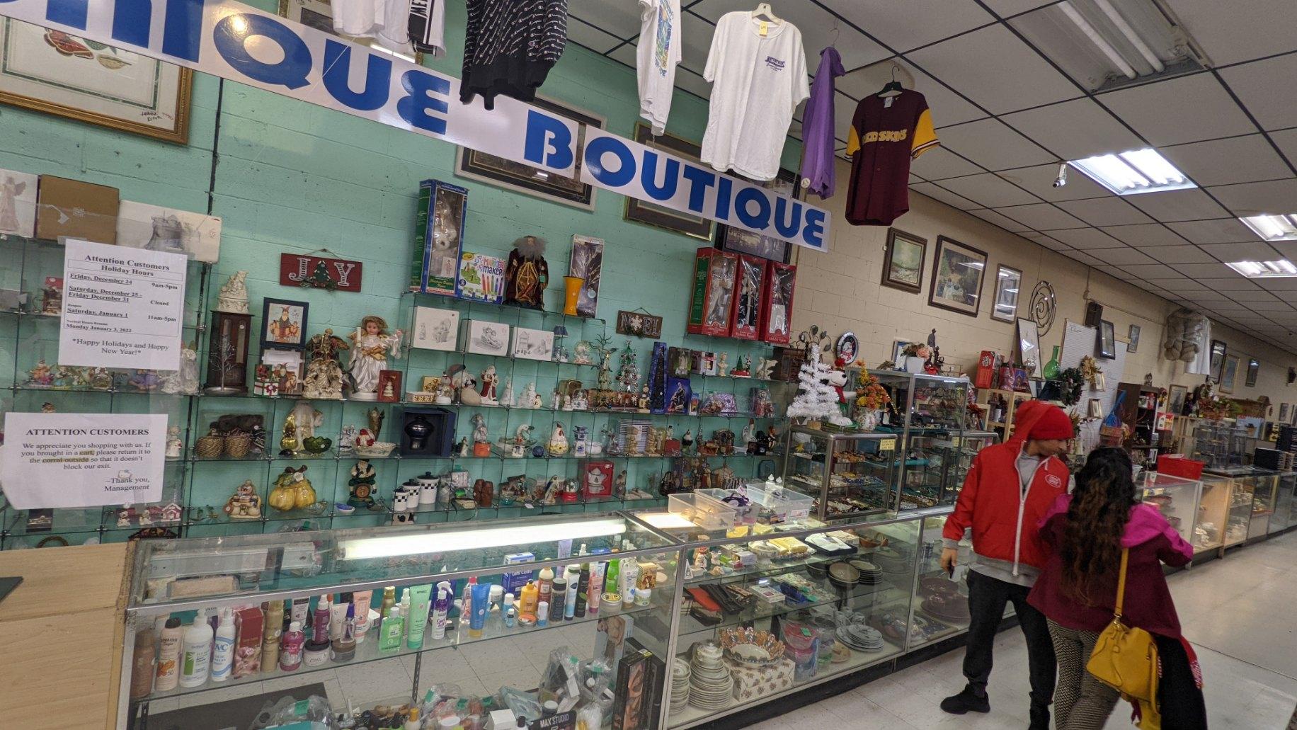 Interior of a shop with shelves of items and customers looking at displays. 