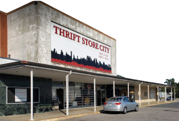 Thrift Store City exterior with a car parked out front; the building has a sign that features a city skyline.