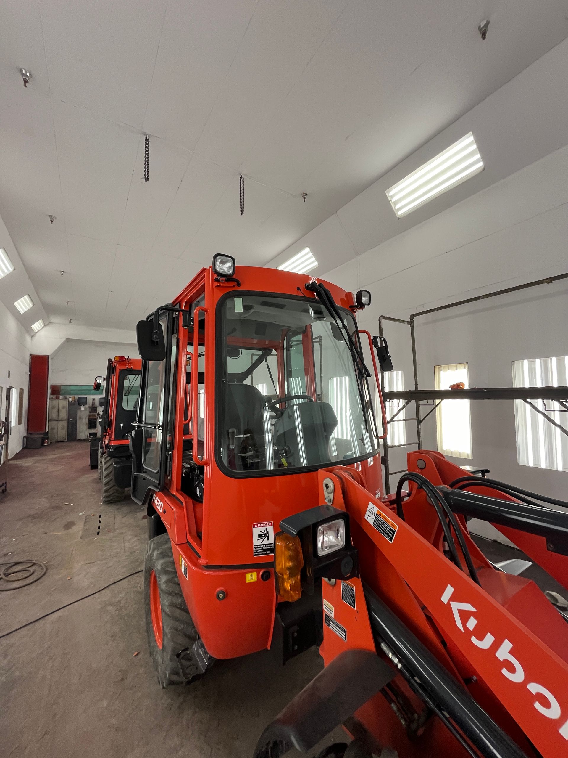 Chargeurs Kubota orange alignés à l'intérieur d'un garage.
