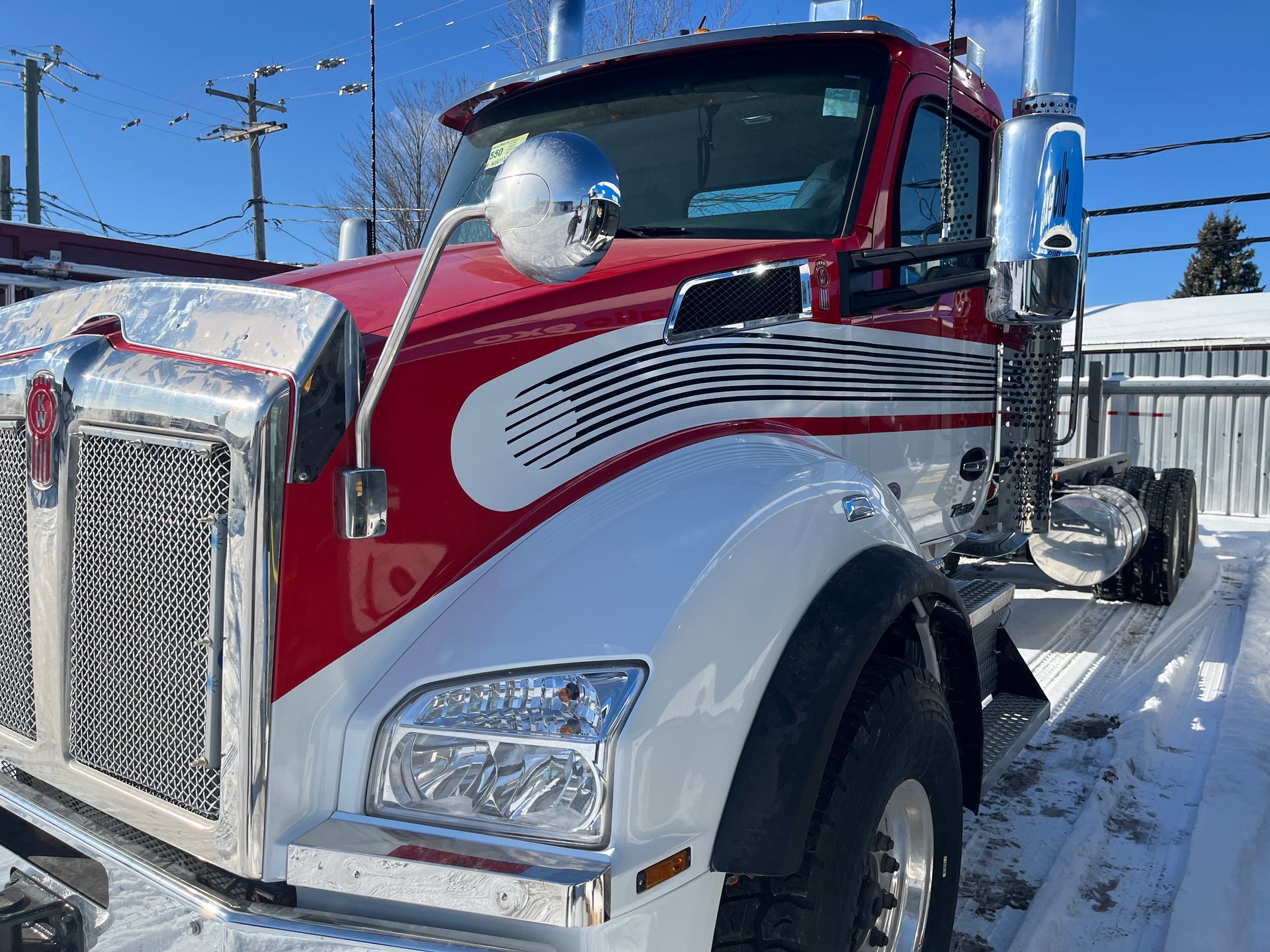 Semi-remorque Kenworth rouge et blanc stationné dans la neige. Calandre et tuyaux chromés.
