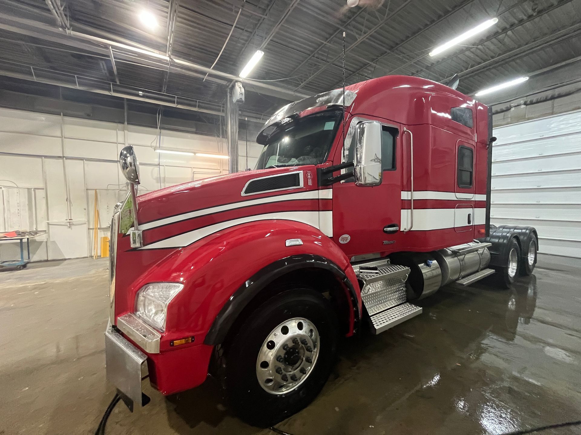 Semi-remorque rouge et blanche dans une station de lavage.