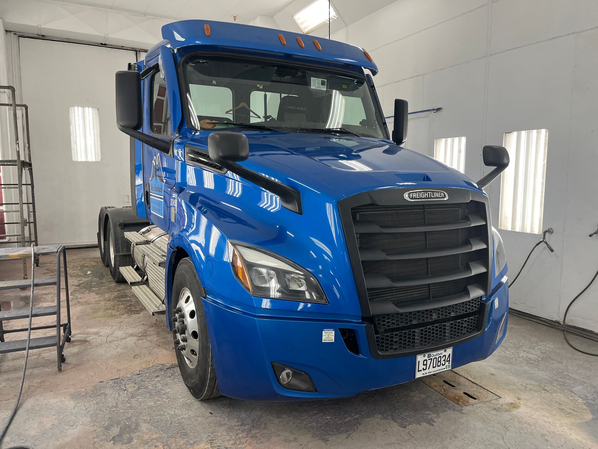 Un semi-remorque Freightliner bleu dans une cabine de peinture, prêt à être peint.