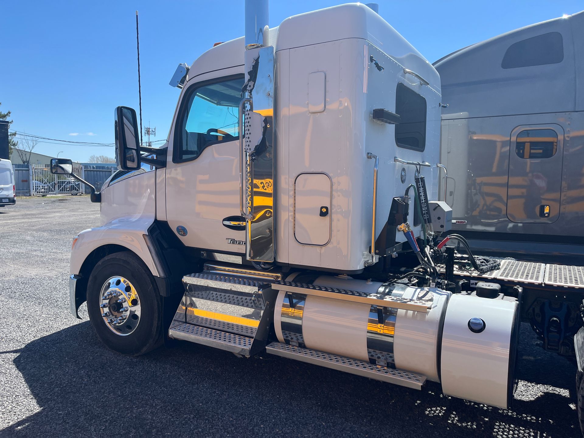Semi-remorque blanc stationné à l'extérieur par une journée ensoleillée. Des touches de chrome sont visibles sur la cabine.