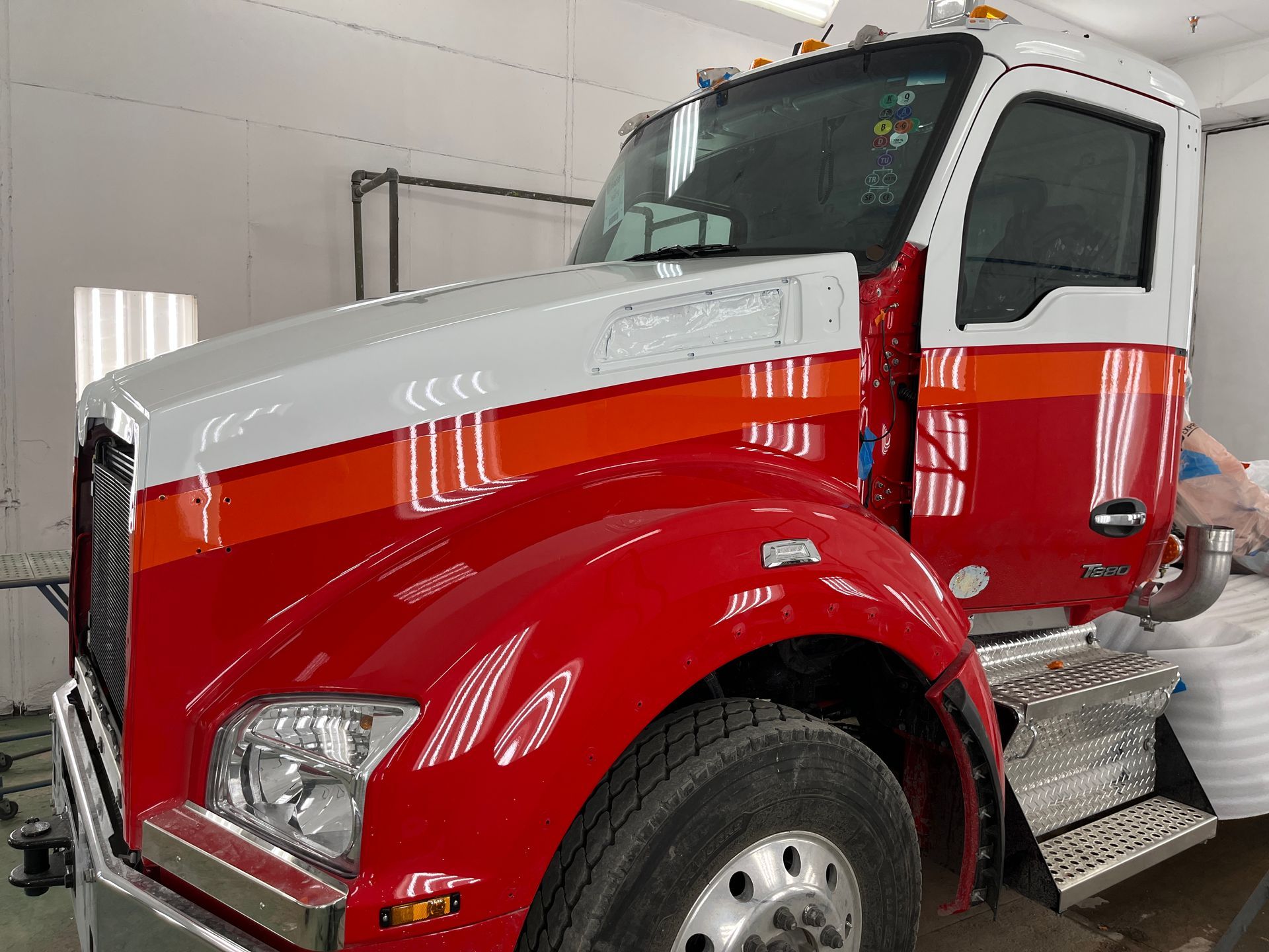 Cabine de semi-remorque rouge, orange et blanche dans un garage.