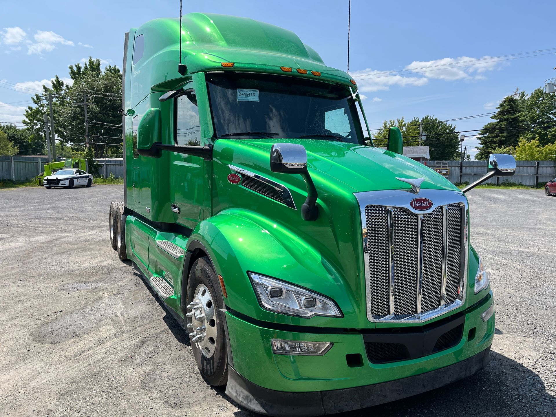 Un semi-remorque Peterbilt vert vif est garé à l'extérieur sur un terrain gravillonné.