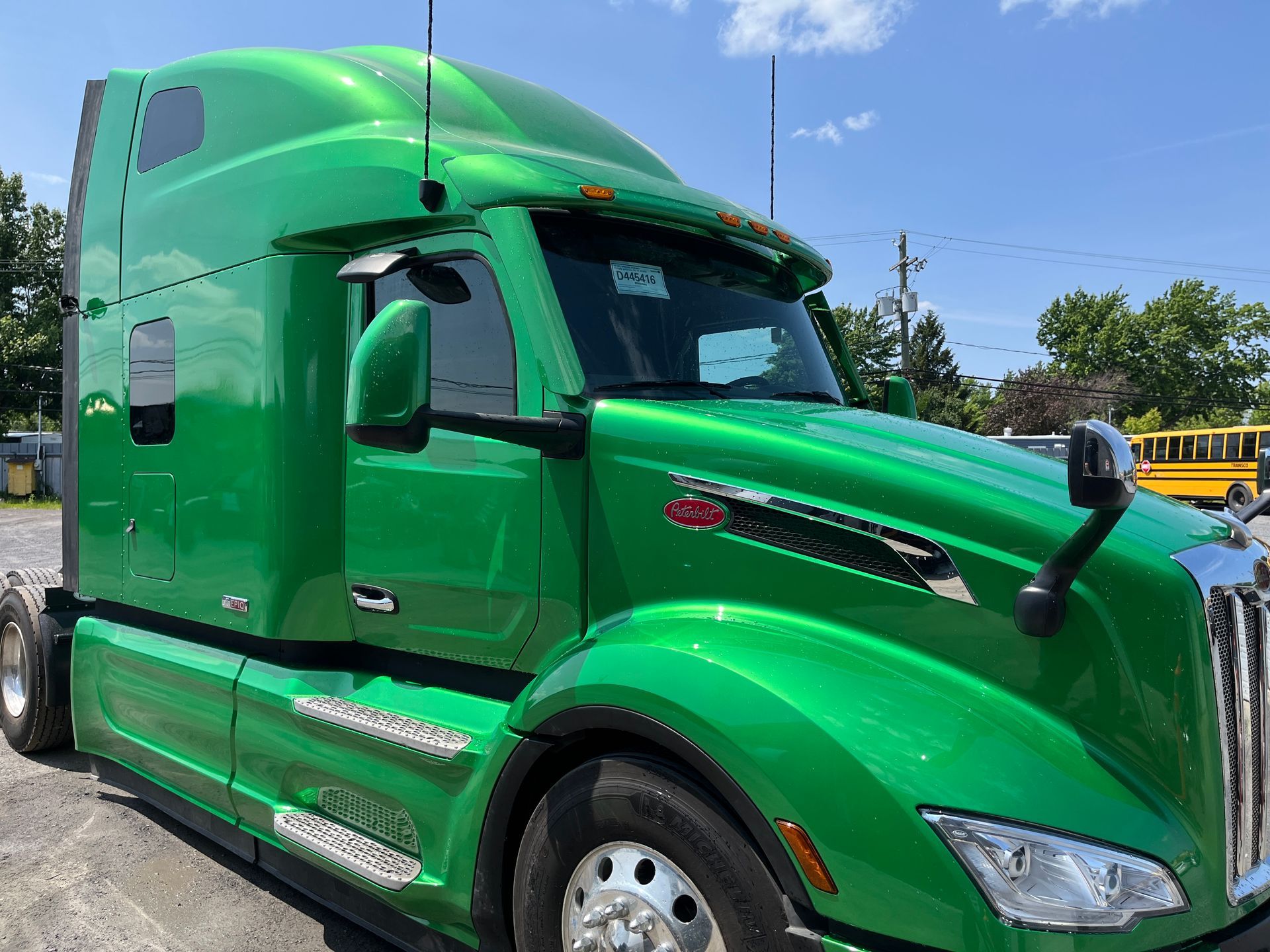 Semi-remorque verte garée à l'extérieur. Brillante, avec une grande cabine et divers détails réfléchissants.