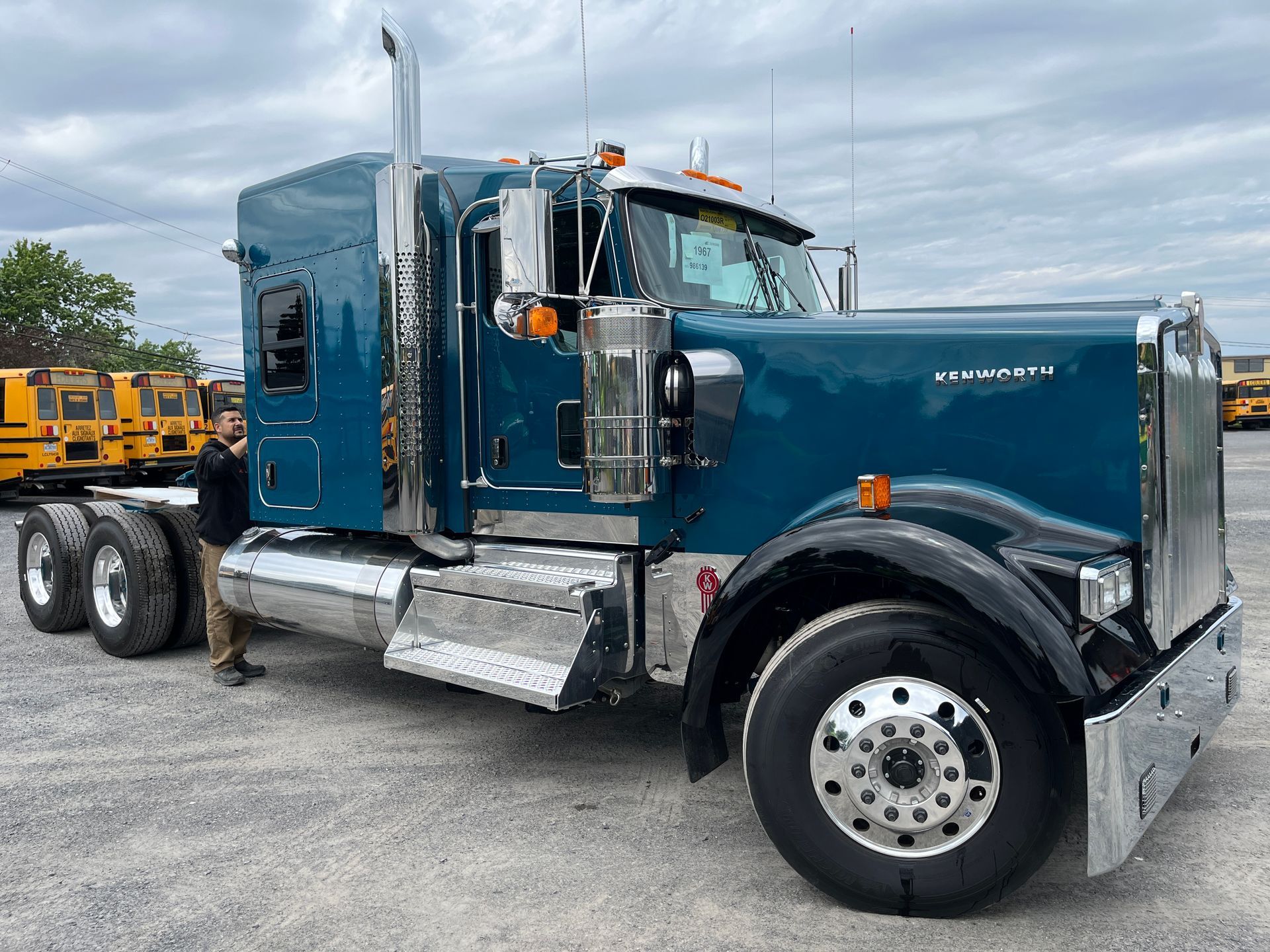 Un semi-remorque bleu est stationné à l'extérieur, avec des éléments chromés. Une personne se tient à proximité.