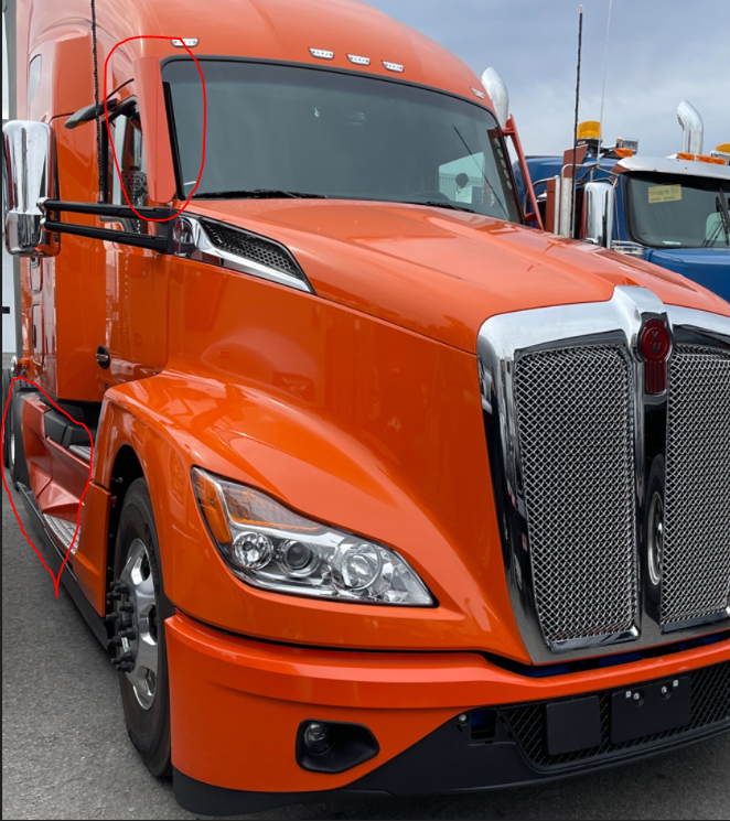 Semi-remorque Kenworth orange garée à l'extérieur. Calandre argentée, touches noires et rétroviseurs chromés.