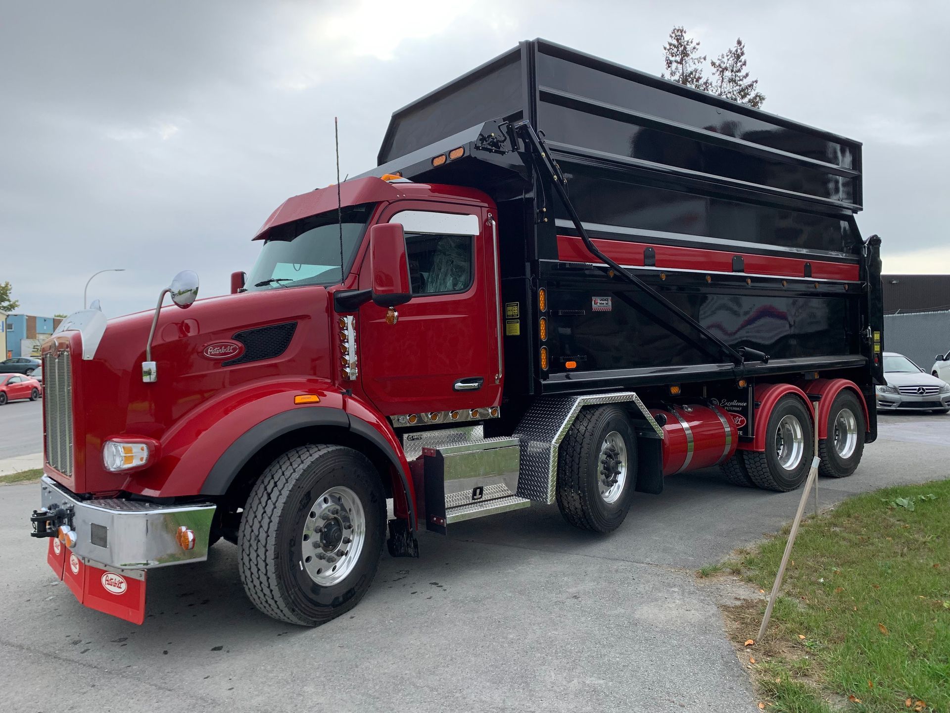 Camion à benne basculante rouge et noir stationné sur l'asphalte.