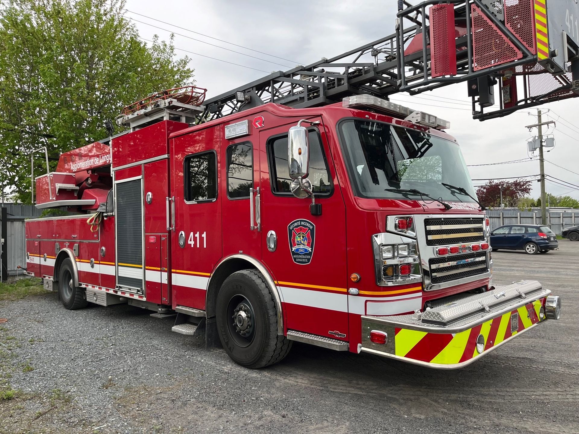Camion de pompiers rouge avec échelle déployée, stationné à l'extérieur.