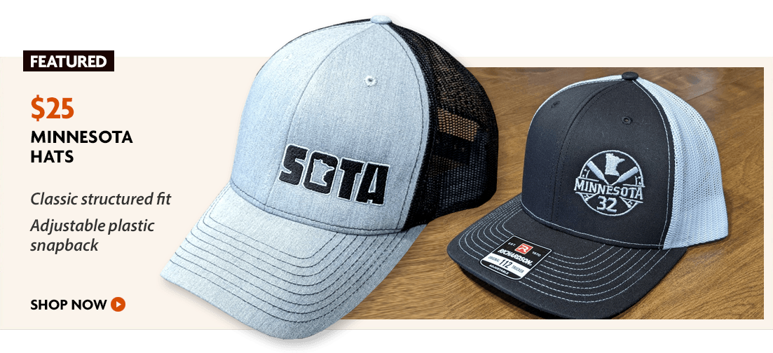 A pair of minnesota hats are sitting on a wooden table.