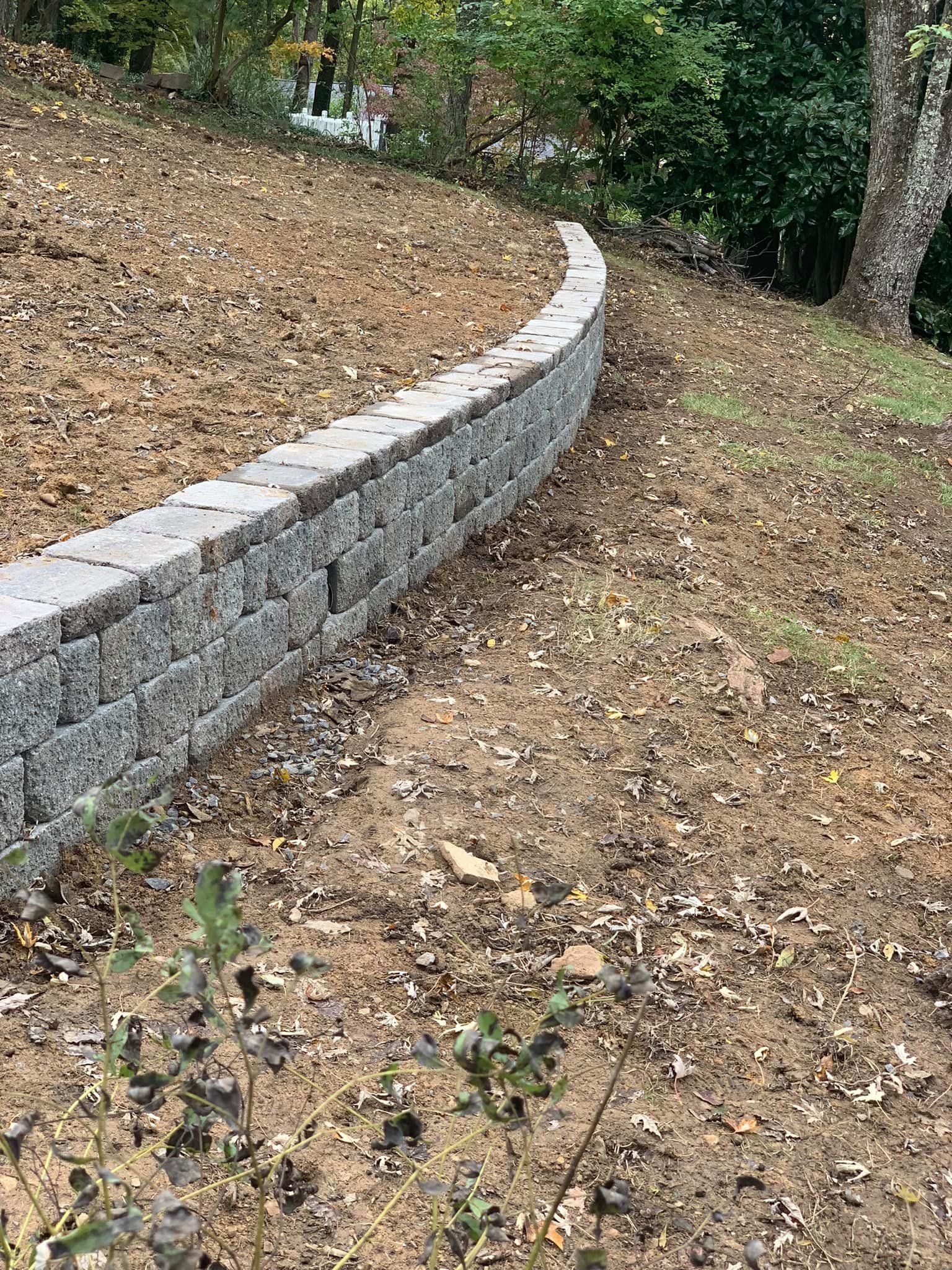 A stone wall is sitting on top of a dirt hill.