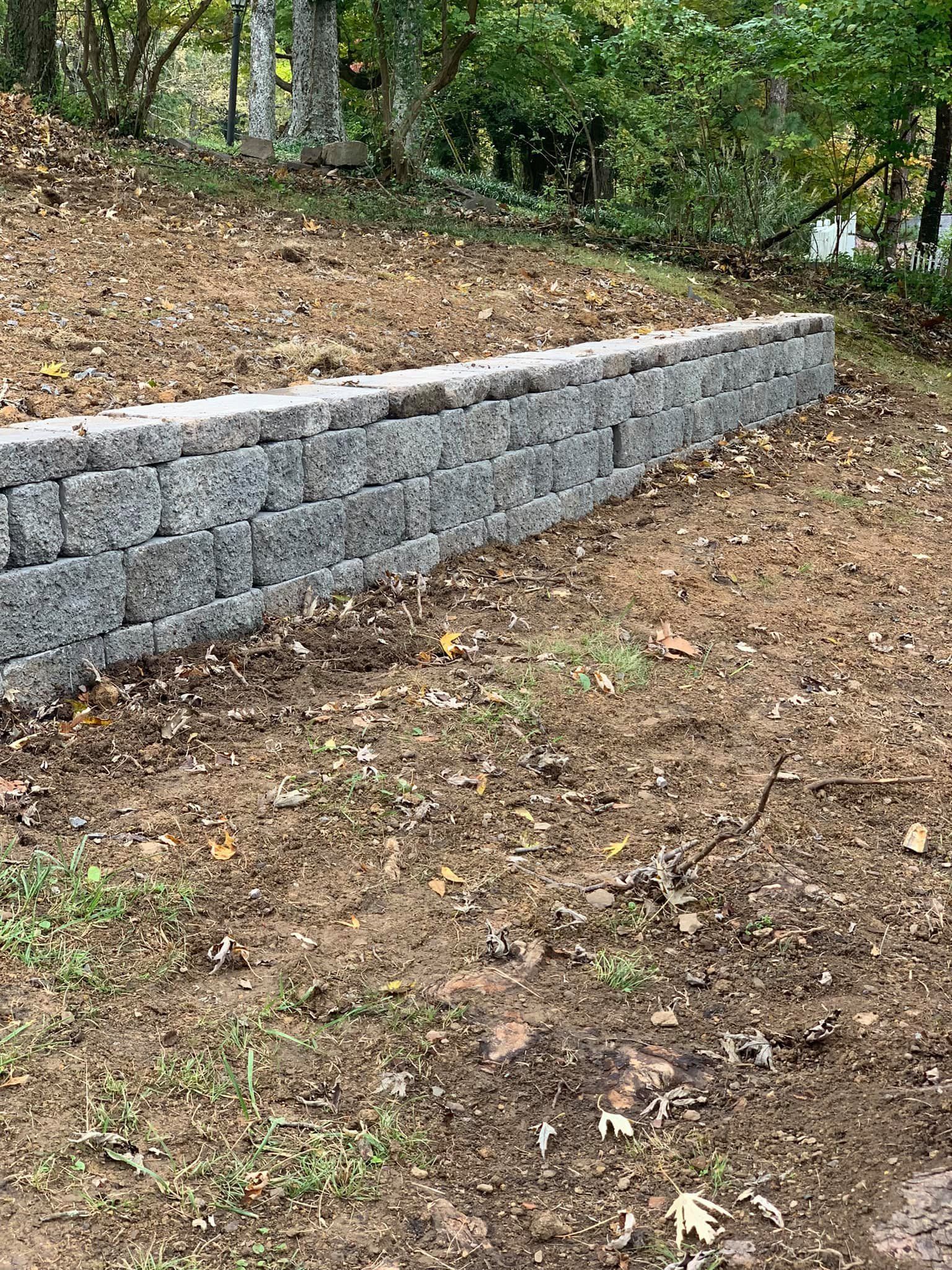 A stone wall is sitting in the middle of a dirt field.