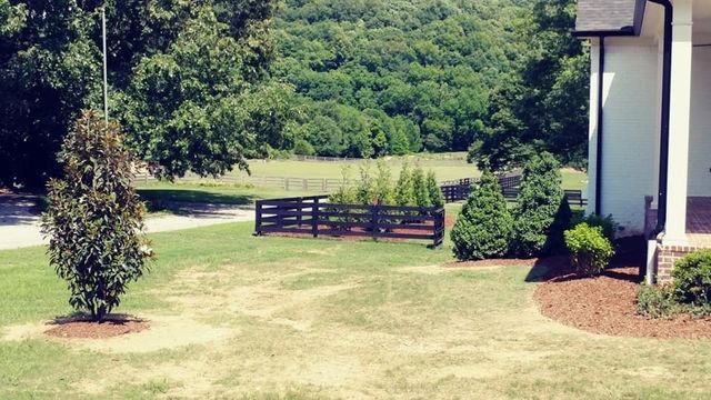 A house with a large lawn and a fence in front of it.