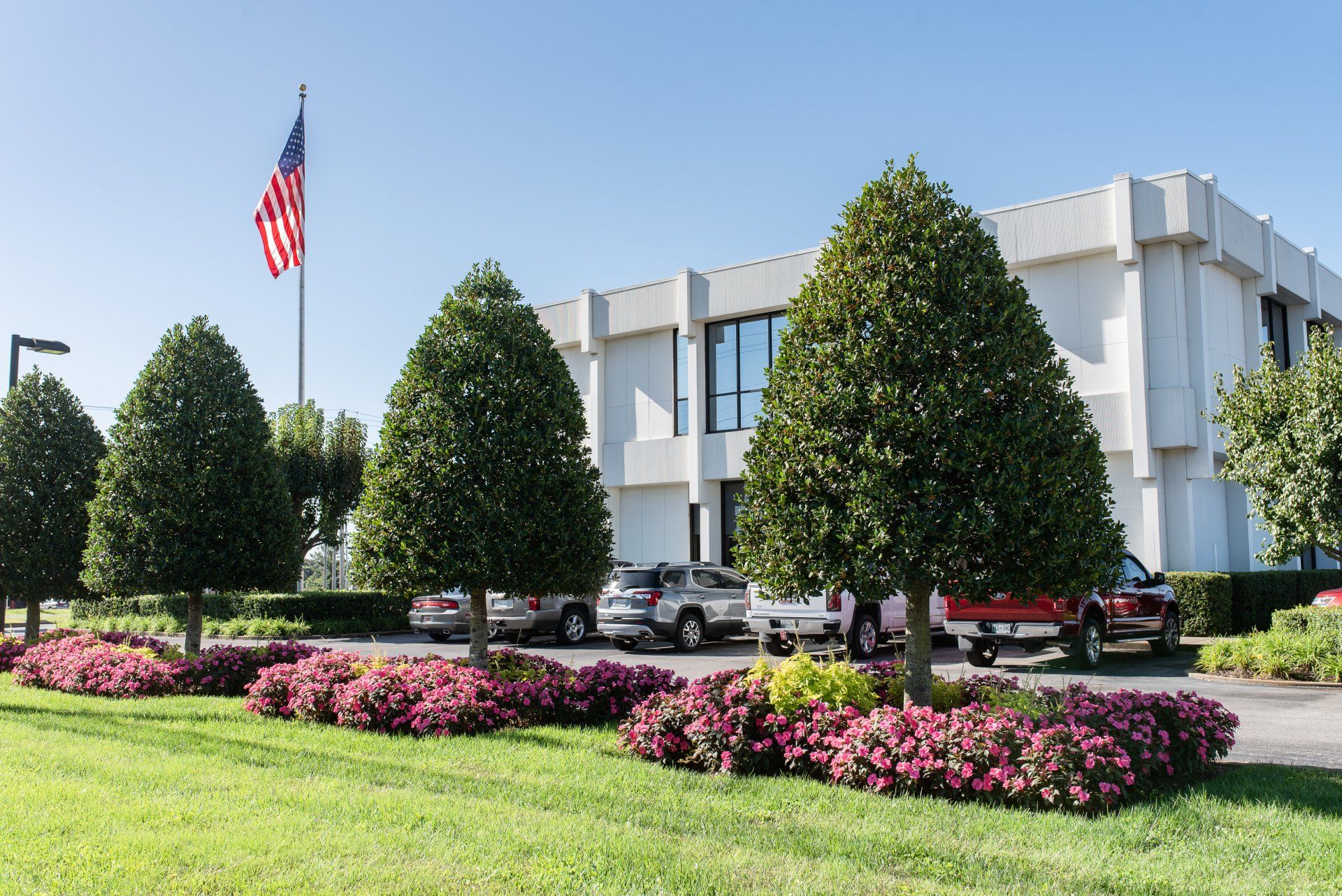 A white building with a red truck parked in front of it.