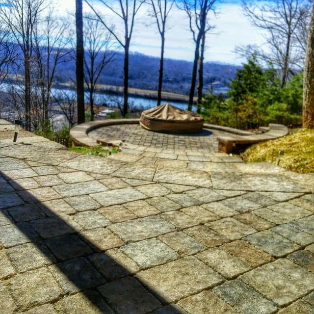 A stone patio with a fire pit and trees in the background