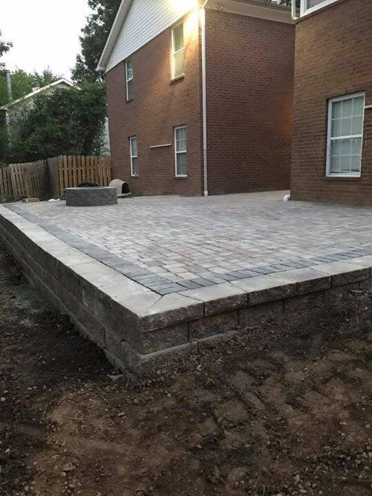 A brick house with a patio and a fire pit in front of it.